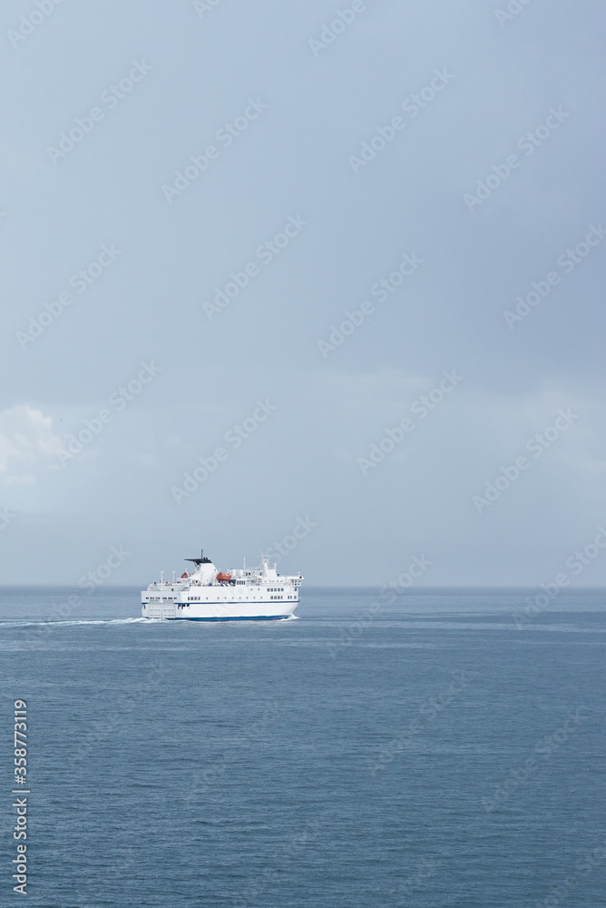 Big white Croatian ferry sailing out of Split going to the islands. Alone on the sea on a rainy storm day, dark clouds stretching into the distance