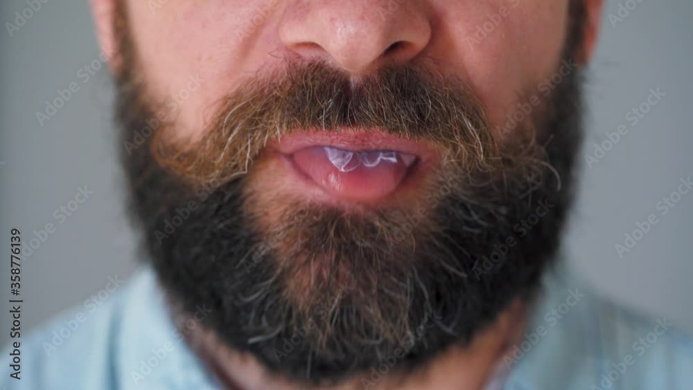 Close-up of a bearded man's mouth chewing chewing gum. Man blowing out a bubble of bubble gum Close-up of a bearded man's mouth chewing chewing gum. Man blowing out a bubble of bubble gum