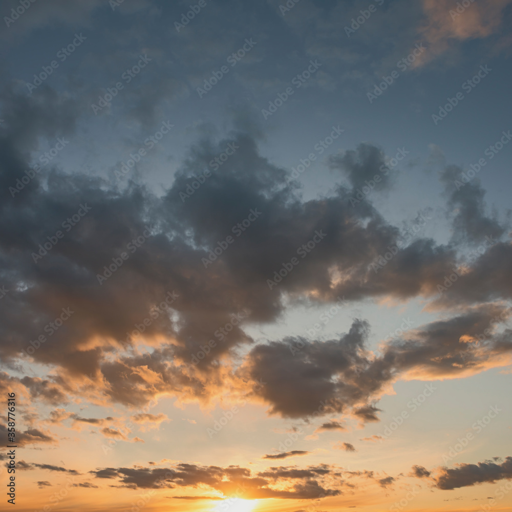 sun sets behind the clouds in the blue evening sky as a natural background sun sets behind the clouds in the blue evening sky as a natural background