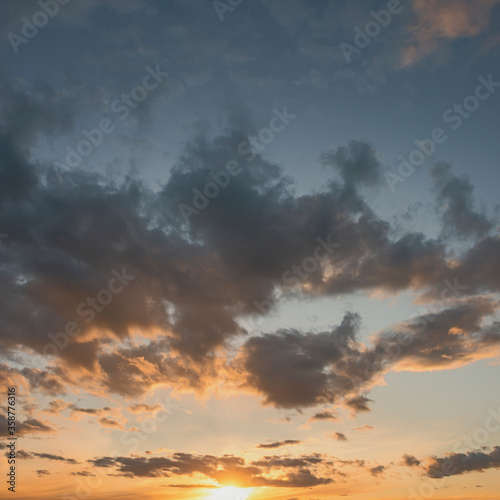 sun sets behind the clouds in the blue evening sky as a natural background
