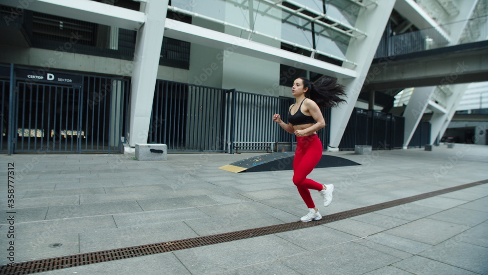 Fitness woman running near stadium in slow motion. Focused athlete girl jogging