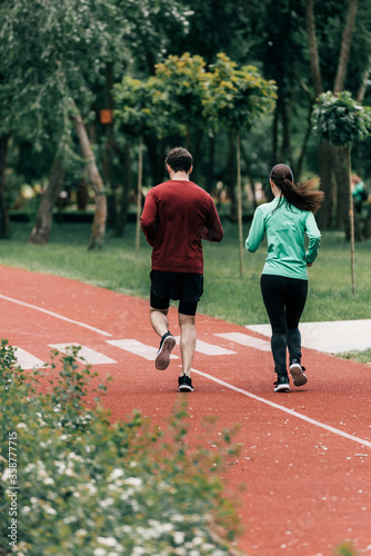 Selective focus of couple running on running path in park