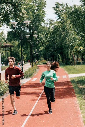Handsome man running near positive girlfriend on running path in park © LIGHTFIELD STUDIOS