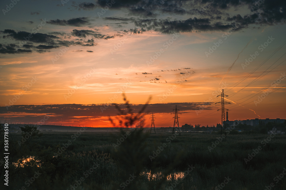 Power line structures in the field against the red sun Power line structures in the field against the red sun