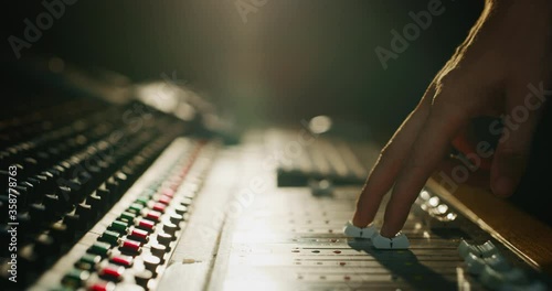 Close up slide shot of a sound producer hand is using a music mixer with editing tools in a professional recording studio.