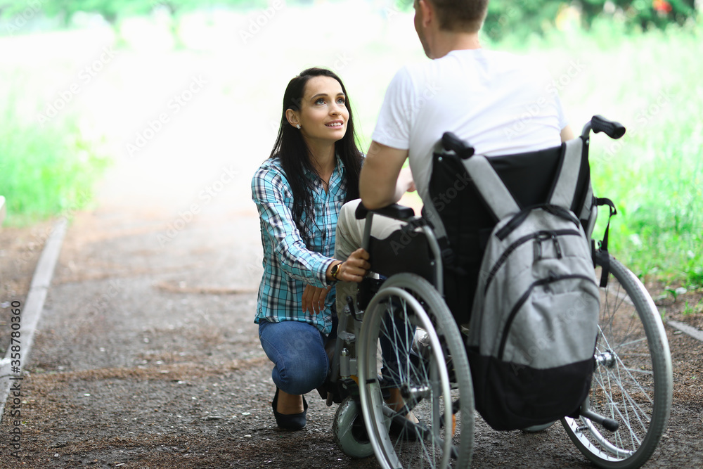 Disabled couple in love on a walk in park portrait. Wife looks at her husband in love with eyes. Rehabilitation disabled person after car accident concept