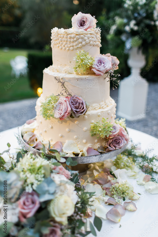 Wedding cake standing on the table. With the flowers.