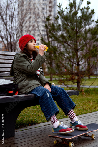 Skateboard girl take pause for juice and sandwich