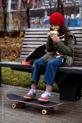 Skateboard girl take pause for juice and sandwich