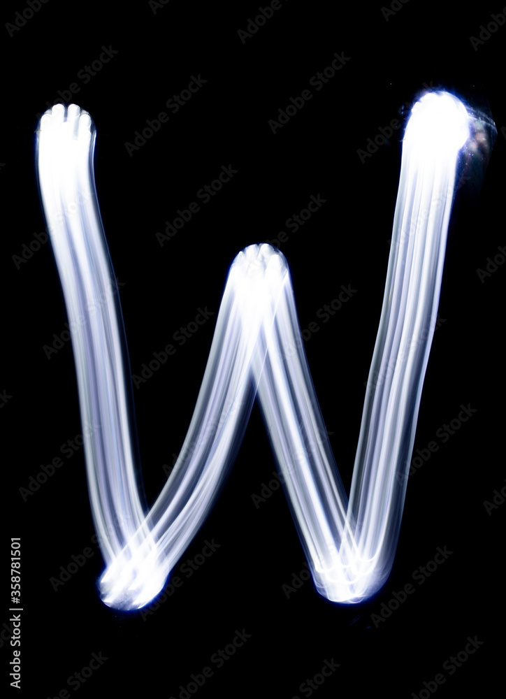 Handwrite letter W, made with light painting technic isolated on black ...