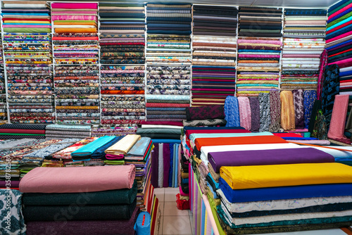 Colorful rolls of fabrics for sale in the market.Rolls of cotton with colorful and beautiful patterns in the shop selling fabrics as rolls of fabric that are woven with machines in the factory. Linens photo