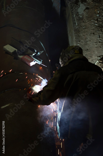 male worker welds steel pipe of household heating at night