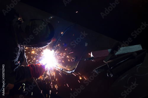 male worker welds steel pipe of household heating at night