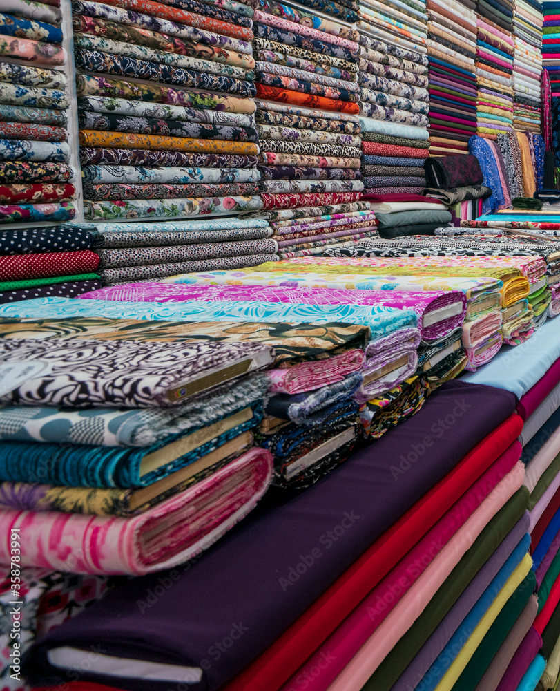 Rolls of fabric and textiles in a factory shop. Multi different colors and patterns on the market Fabrics in rolls. floral pattern, various colors, colorful. Woven fabrics Rolls of fabric and textiles in a factory shop. Multi different colors and patterns on the market Fabrics in rolls. floral pattern, various colors, colorful. Woven fabrics