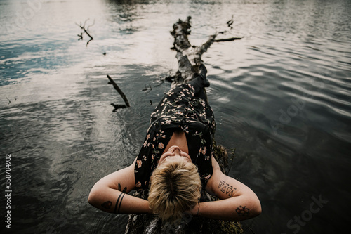 Europe, Germany, Berlin, Mueggelheim, Grosse Krampe, woman relaxing on a tree in the lake.