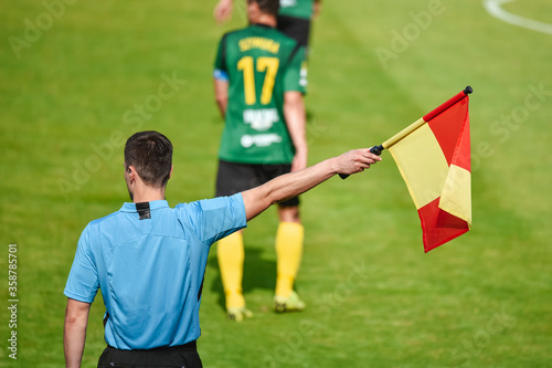 Assistant of football referee with rised flag.