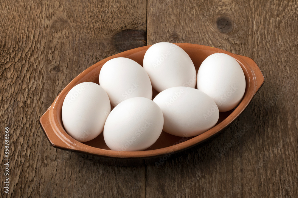 Six white eggs into a bowl on a wooden table. Six white eggs into a bowl on a wooden table.