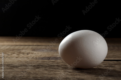 A fresh white egg on a wooden table.