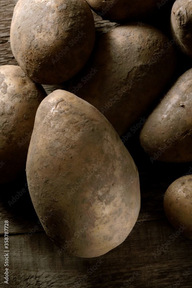 Fresh biologic yellow potatos on a wooden table.