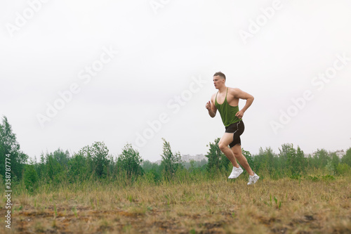 A man runs through the woods in a T-shirt and sports shorts through the park. Morning Jogging