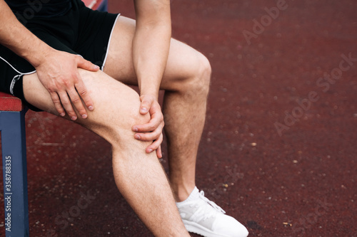 A big plan is male athlete holding on to his knee. The concept of falling during sports. Break a leg in training
