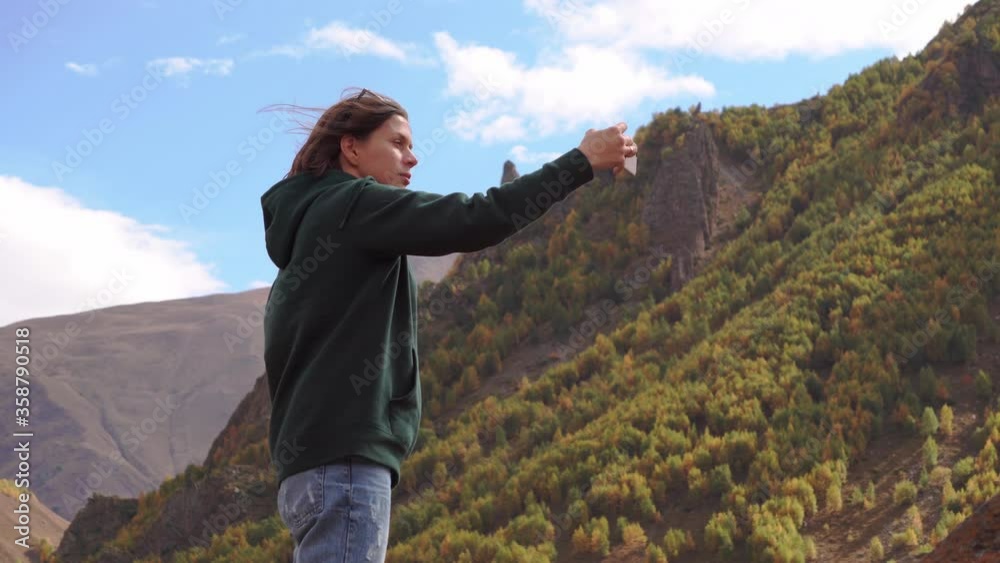 a girl photographs herself against the background of mountains