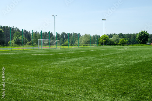 Soccer field with green artificial lawn and football goal on the background.