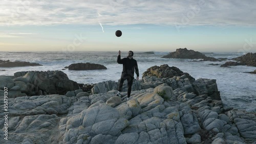 Slow motion cinematic of authentic and trendy basketball player in black sport suit practacing with ball at sunset filled california vibes on warm summer evening