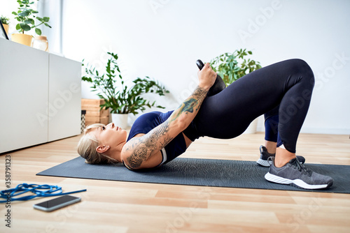 Athletic woman doing kettlebell hip raises during home workout