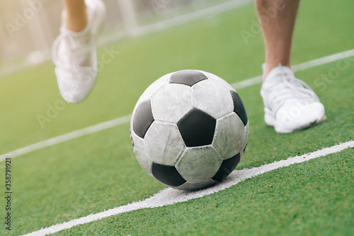 The legs of the football closeup next to the football. concept scores a goal to pass to another player during the game ©  drugoenebo