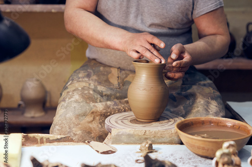 Potter at work. Workshop place. The hands of a potter creating jar on the circle.