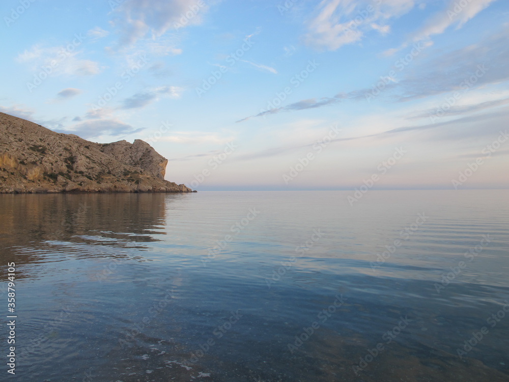 Sunset by the sea. Calm, sky and sea in pastel pink and blue tones. Mirror surface of the sea. Cape Alchak, Black sea