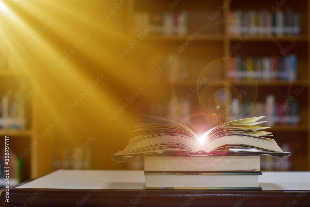 Open Book on wood table and blurred bookshelf in the library, education background, back to school concept. Open Book on wood table and blurred bookshelf in the library, education background, back to school concept.
