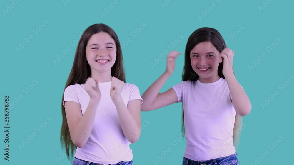 Amazed european twins shocked, saying WOW, jumping, waving their hands and laughing. Good-looking young sisters with long hair surprised to camera over blue background. Family and happiness concept. Amazed european twins shocked, saying WOW, jumping, waving their hands and laughing. Good-looking young sisters with long hair surprised to camera over blue background. Family and happiness concept.