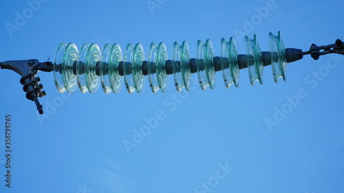 High-voltage electrical insulator of the electric line on a background of blue sky. Portal of the high voltage line.