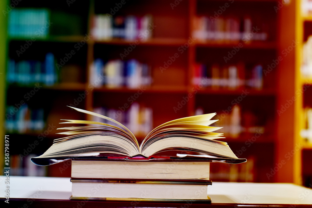 Open Book on wood table and blurred bookshelf in the library, education background, back to school concept. Open Book on wood table and blurred bookshelf in the library, education background, back to school concept.