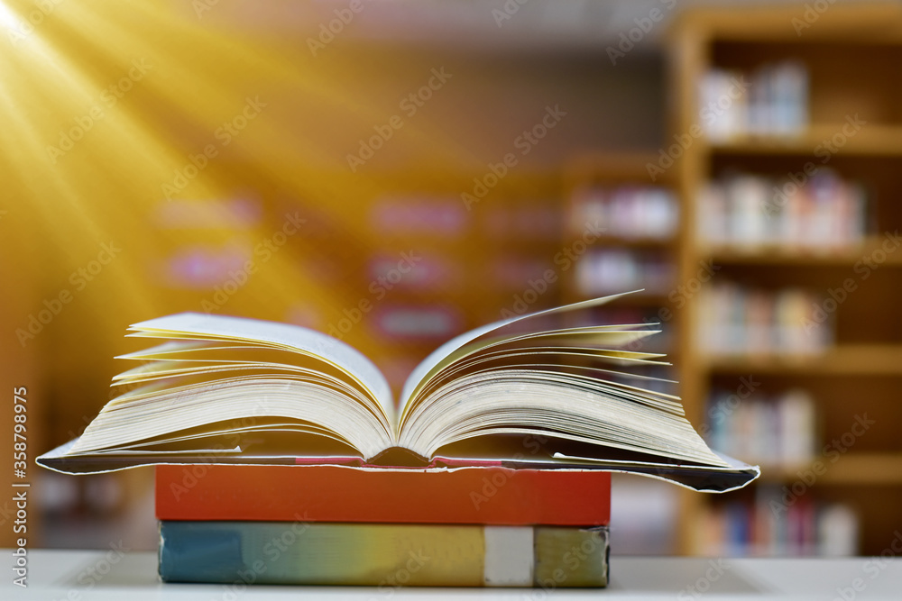 Open Book on wood table and blurred bookshelf in the library, education background, back to school concept. Open Book on wood table and blurred bookshelf in the library, education background, back to school concept.