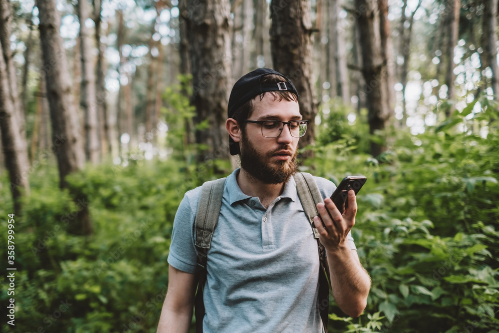 A young man using a smartphone in the forest. Tourism, active lifestyle. A young man using a smartphone in the forest. Tourism, active lifestyle.