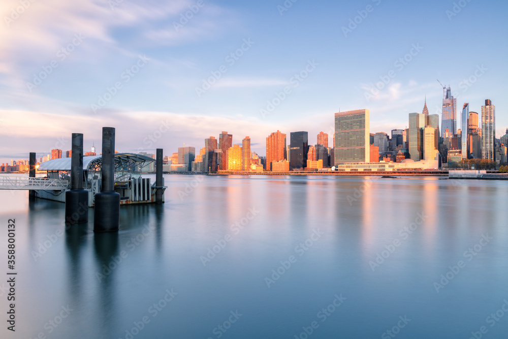 View on Midtown Manhattan and from East river with ferry stop during sunrise with long exposure