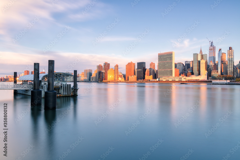 View on Midtown Manhattan and from East river with ferry stop during sunrise with long exposure View on Midtown Manhattan and from East river with ferry stop during sunrise with long exposure