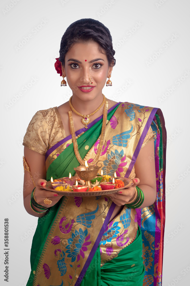 An young and beautiful Indian Maharashtrian woman in Green traditional ethnic saree holding a puja thali showing Indian culture, religion and fashion
