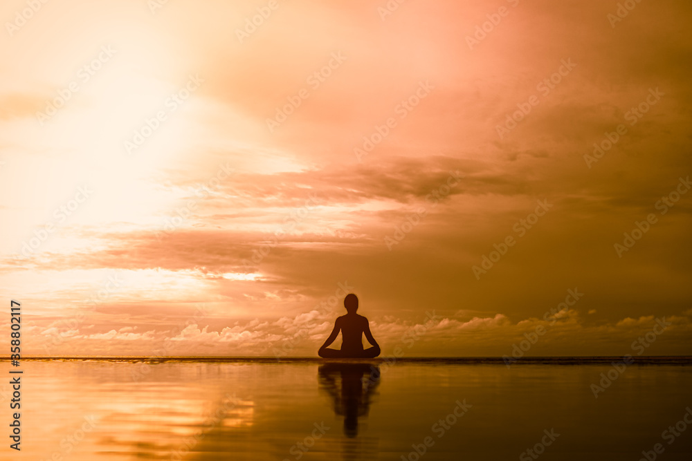 silhouette Young woman practicing yoga outdoor on the beach in morning