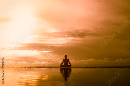 silhouette Young woman practicing yoga outdoor on the beach in morning