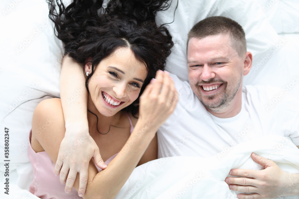 Happy caucasian beatyful couple lie on bed top view portrait. Healthy family concept Happy caucasian beatyful couple lie on bed top view portrait. Healthy family concept