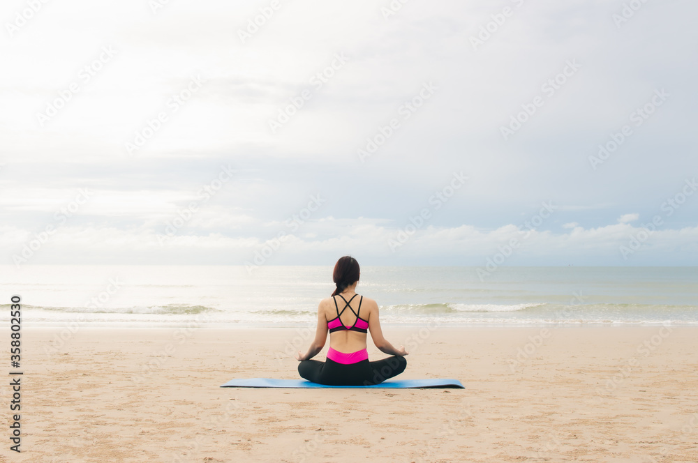 Young woman practicing yoga outdoor on the beach in morning
