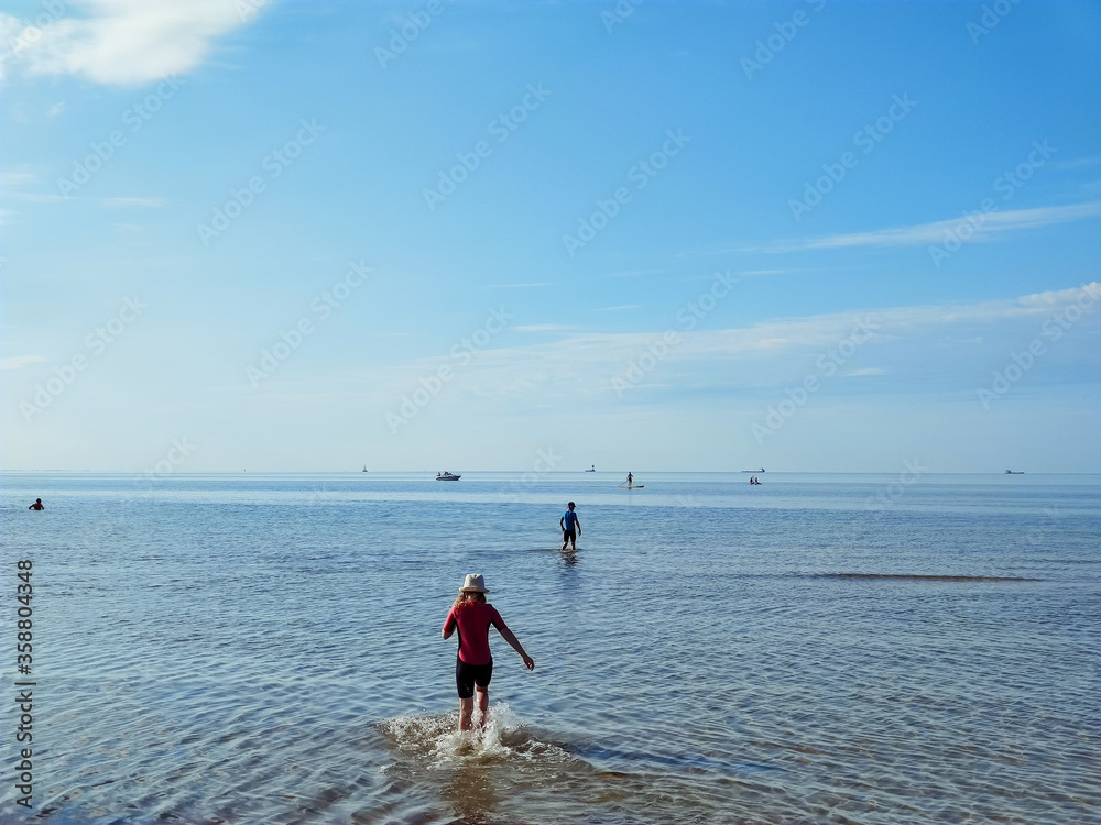 Two happy siblings children in neoprene swimingsuit  playin and running in sea