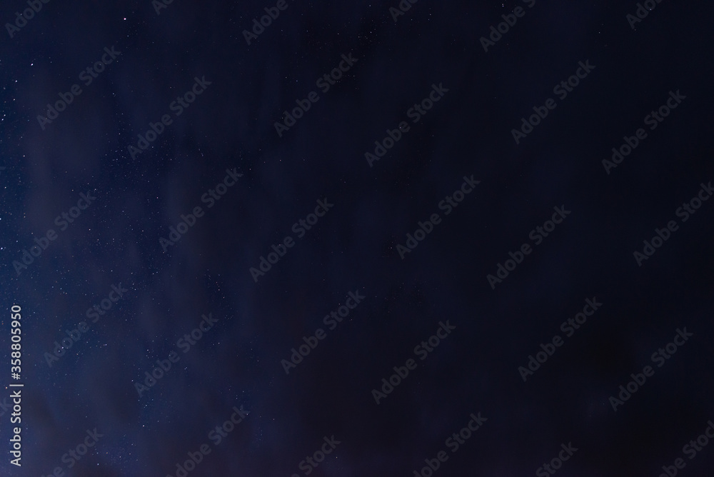 Stars in the night sky through the clouds on a summer night