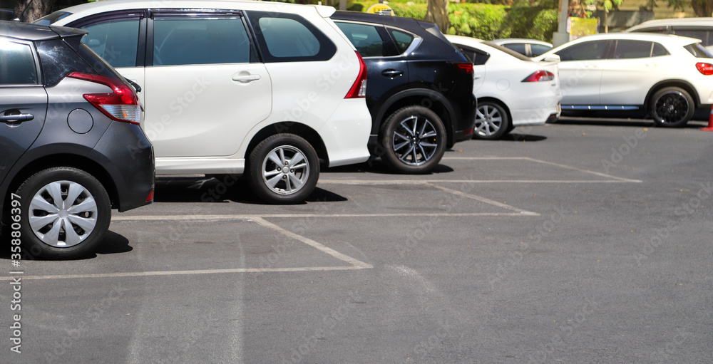 Fototapeta premium Zbliżenie z tyłu, z tyłu czarny samochód z innymi samochodami parkowanie na odkrytym parkingu w jasny, słoneczny dzień.