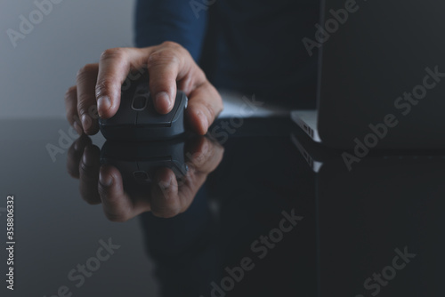Close up of man hand clicking wireless mouse while working on laptop computer