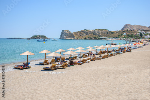 Stegna beach with sunbeds and umbrellas, holidaymakers sun bathing (RHODES, GREECE)